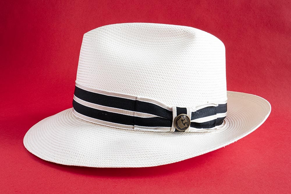 side angle straw fedora hat with blue ribbon band and teardrop crown embellishment 